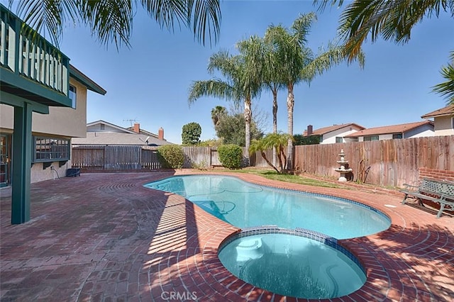 view of swimming pool with a fenced backyard, a pool with connected hot tub, and a patio