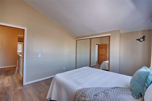 bedroom featuring baseboards, lofted ceiling, a closet, and wood finished floors