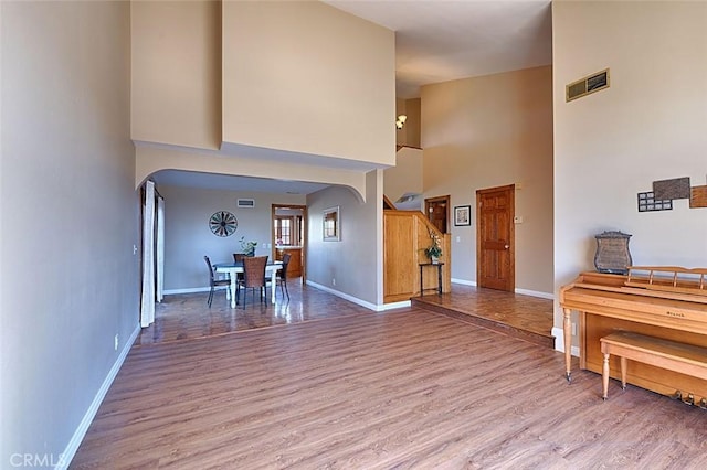 entryway with visible vents, baseboards, arched walkways, and light wood finished floors