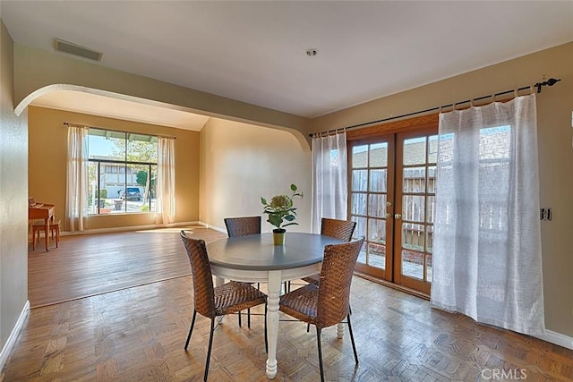 dining area with arched walkways, french doors, and baseboards