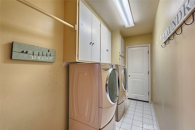 laundry area with separate washer and dryer, light tile patterned floors, and cabinet space