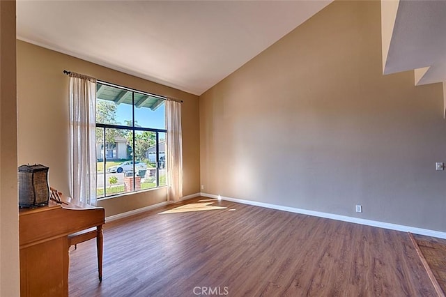 unfurnished room with lofted ceiling, baseboards, and dark wood-type flooring