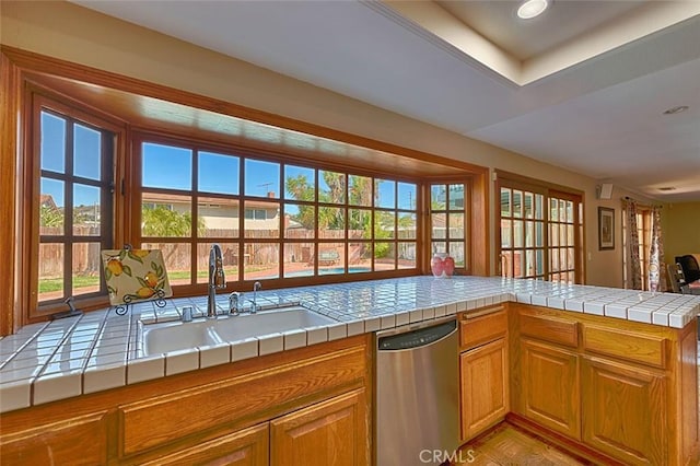 kitchen featuring tile countertops, dishwasher, brown cabinets, and a sink