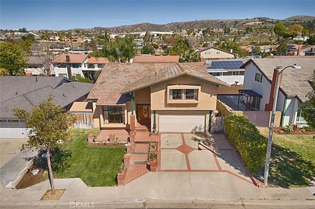 view of front facade with a garage, a residential view, concrete driveway, and a mountain view