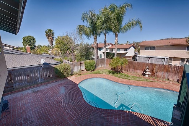 view of pool featuring a patio area, a fenced backyard, a fenced in pool, and a residential view