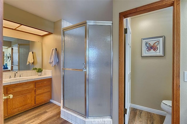 full bathroom with baseboards, vanity, wood finished floors, and a shower stall