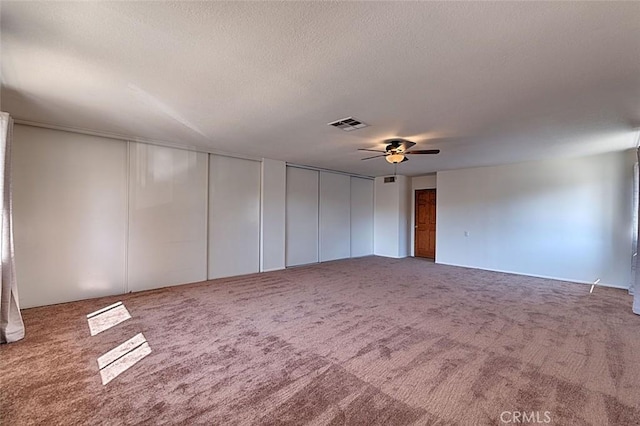 empty room featuring visible vents, carpet floors, a textured ceiling, and ceiling fan