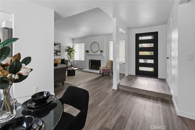 foyer featuring a fireplace, baseboards, and wood finished floors