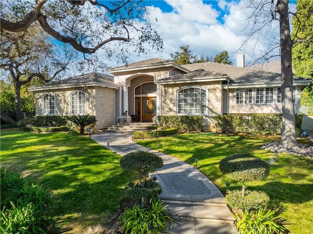 view of front of property featuring a chimney, a front lawn, and stucco siding