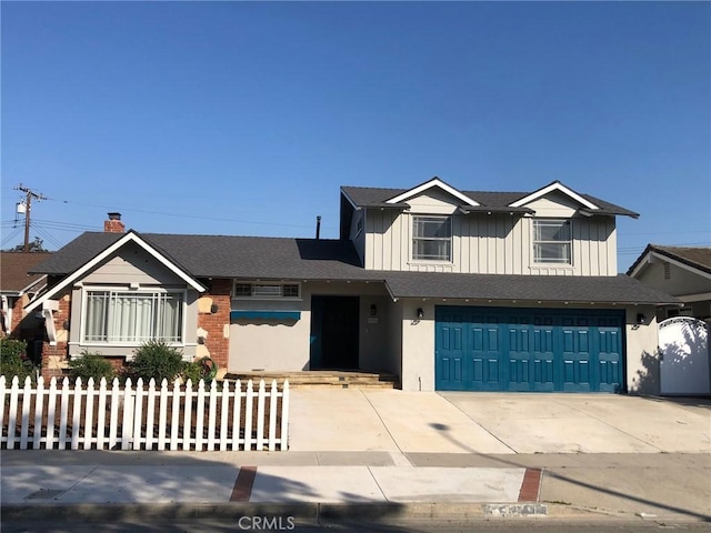 view of front of property featuring board and batten siding, a fenced front yard, a garage, and concrete driveway