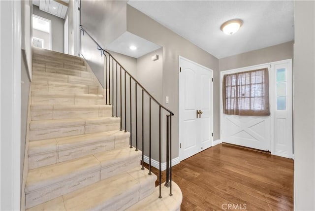 foyer featuring wood finished floors, baseboards, and stairs