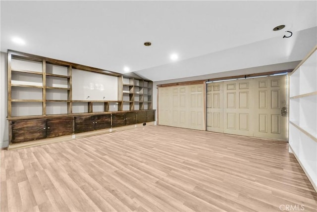 below grade area with light wood-style flooring and recessed lighting