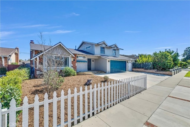 view of front of property with concrete driveway, a fenced front yard, and board and batten siding