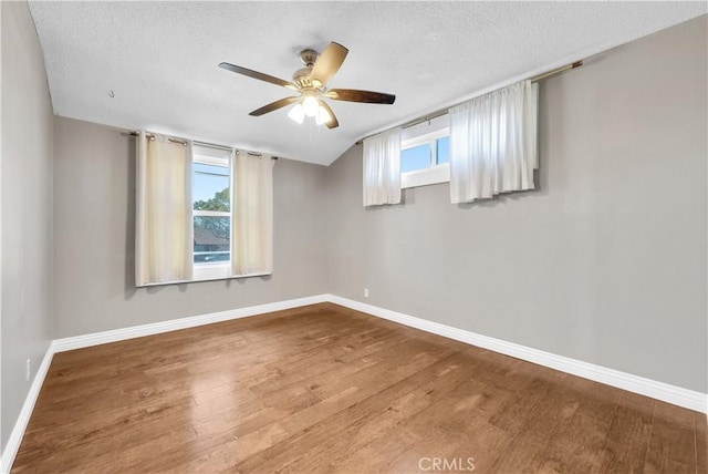 unfurnished room featuring ceiling fan, a textured ceiling, baseboards, and wood finished floors