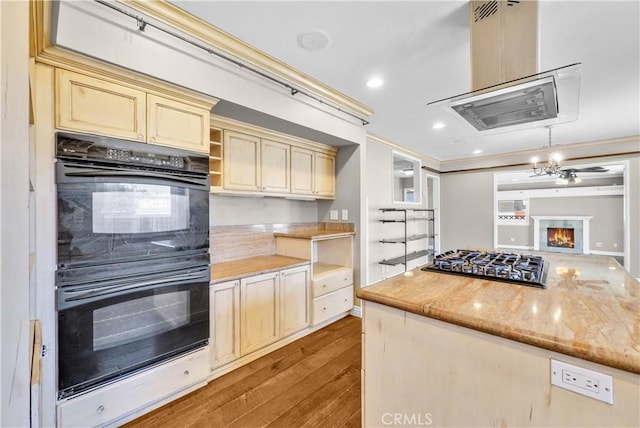 kitchen with crown molding, dobule oven black, stainless steel gas stovetop, and cream cabinets