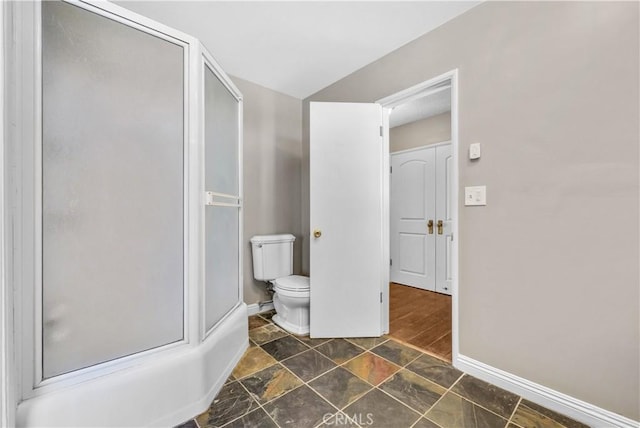 full bath with toilet, stone finish floor, baseboards, and a shower with shower door