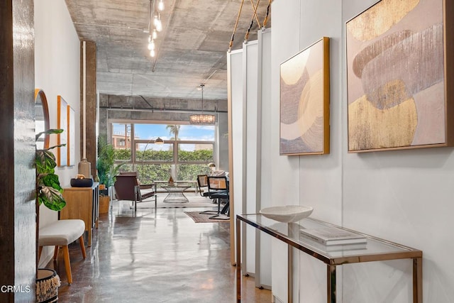 hall featuring concrete floors and a notable chandelier