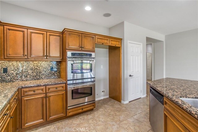 60310 Desert Rose Dr, La Quinta, CA 92253 - kitchen with appliances with stainless steel finishes, brown cabinets, backsplash, and dark stone counters