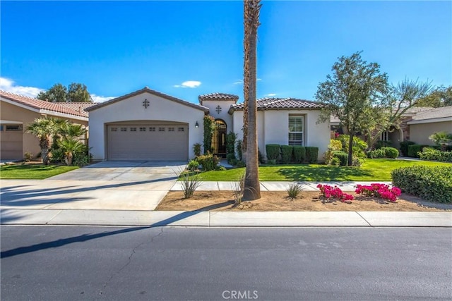 mediterranean / spanish-style home with driveway, stucco siding, a tiled roof, an attached garage, and a front yard