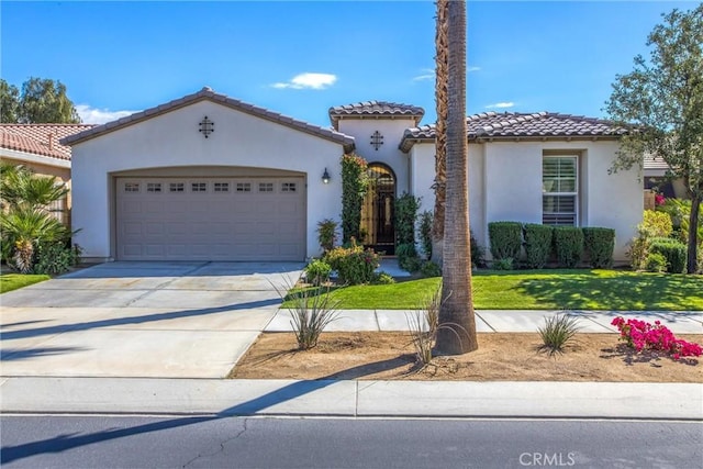 mediterranean / spanish-style home with a garage, a tile roof, driveway, stucco siding, and a front yard