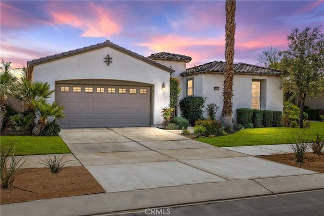 mediterranean / spanish-style home featuring a garage, concrete driveway, a tiled roof, and stucco siding