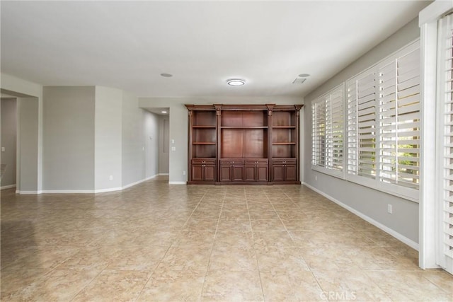 spare room with baseboards and light tile patterned flooring