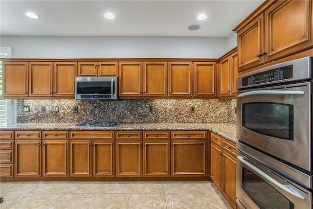 60310 Desert Rose Dr, La Quinta, CA 92253 - kitchen featuring stainless steel appliances, brown cabinets, stone counters, backsplash, and recessed lighting