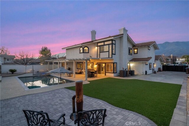 14201 Ross Ct, Rancho Cucamonga, CA 91739 - back of property at dusk featuring a fenced backyard, a patio, a chimney, and stucco siding