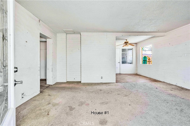 carpeted spare room featuring brick wall and a textured ceiling