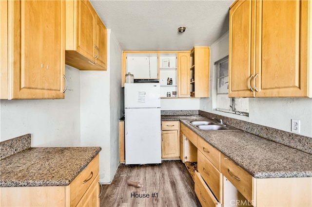 kitchen with dark stone counters, dark wood-style floors, freestanding refrigerator, a textured ceiling, and a sink