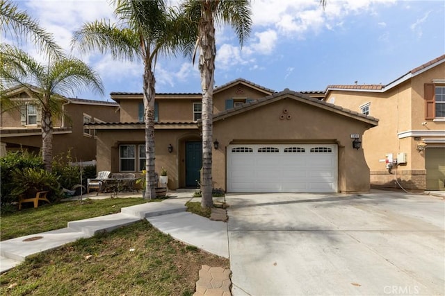 mediterranean / spanish-style house with a garage, driveway, and stucco siding