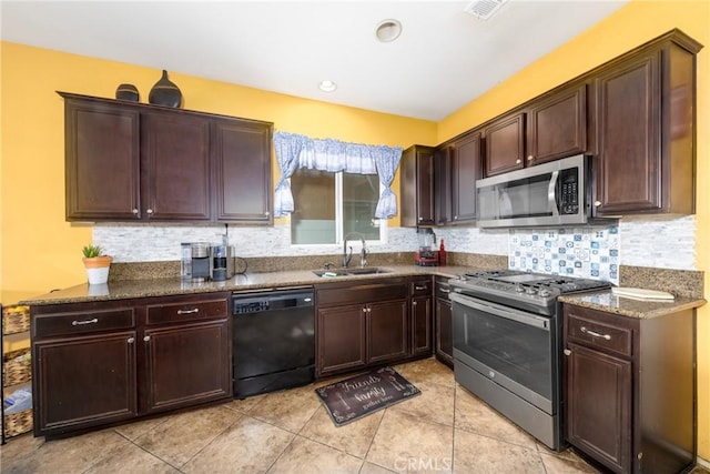 kitchen featuring light tile patterned floors, tasteful backsplash, dark stone counters, appliances with stainless steel finishes, and a sink