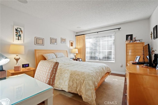 bedroom with baseboards, a textured ceiling, and wood finished floors