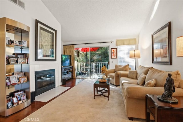 living area with visible vents, a fireplace with flush hearth, a textured ceiling, and wood finished floors
