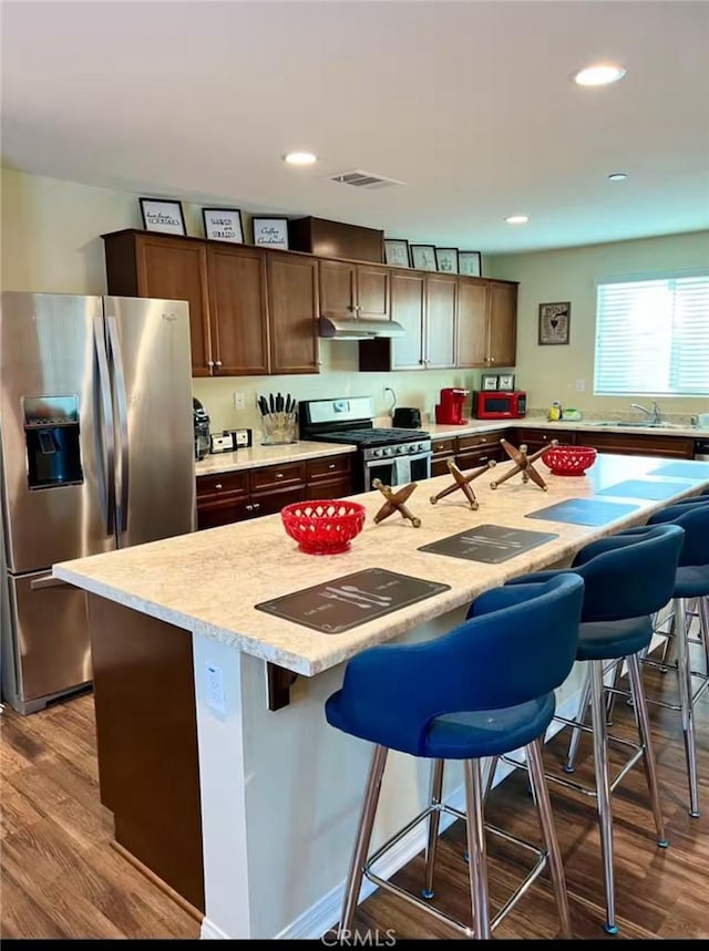 kitchen with appliances with stainless steel finishes, a breakfast bar, light countertops, and a center island with sink