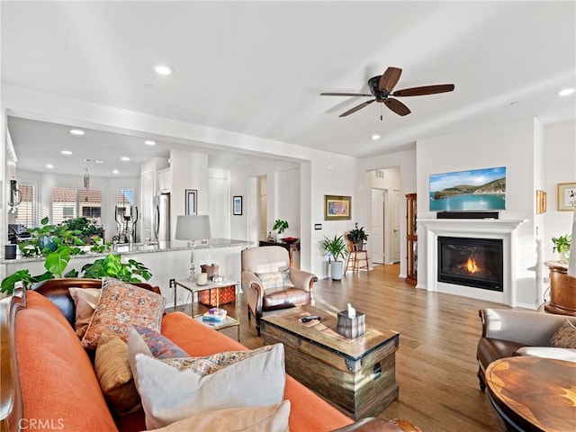 living room featuring light wood-type flooring, a glass covered fireplace, and recessed lighting