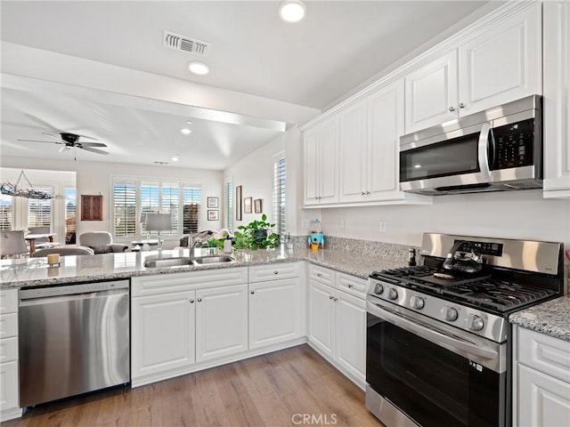 kitchen with stainless steel appliances, a sink, visible vents, and white cabinets