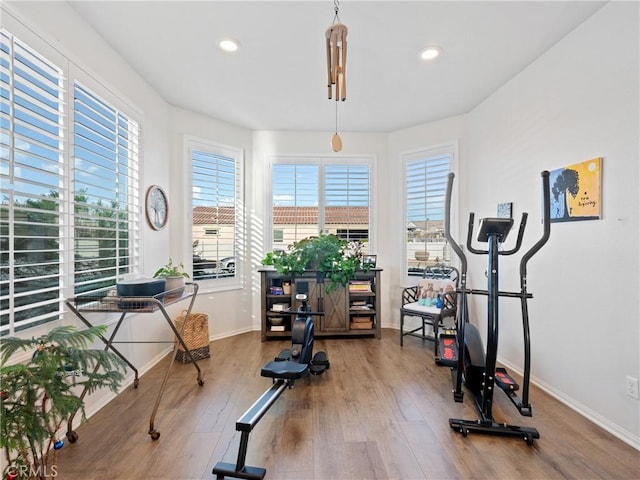 exercise area featuring recessed lighting, wood finished floors, and baseboards