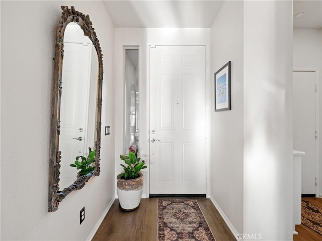 foyer entrance with dark wood-style flooring and baseboards