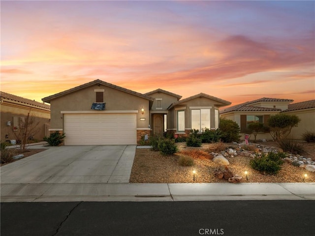 view of front of house with a garage, stone siding, driveway, and stucco siding