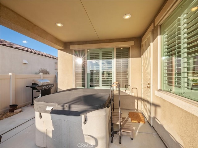 view of patio with a hot tub, fence, and area for grilling