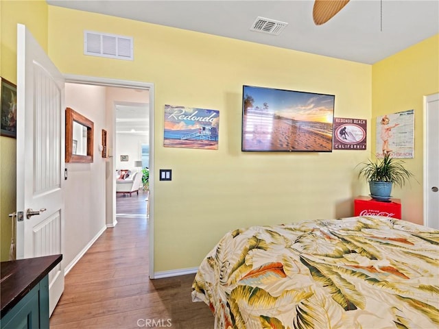 bedroom featuring dark wood-type flooring, visible vents, baseboards, and a ceiling fan