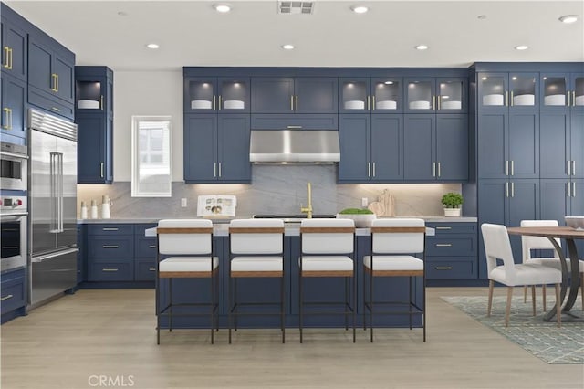 kitchen featuring blue cabinets, appliances with stainless steel finishes, and under cabinet range hood