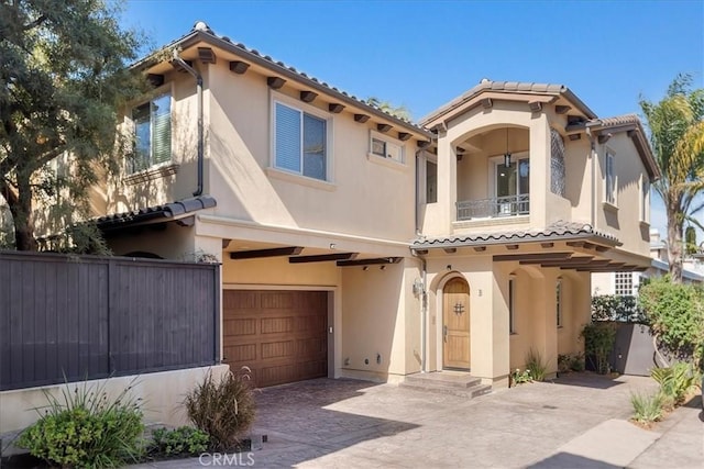 mediterranean / spanish-style house with a garage, a balcony, a tiled roof, decorative driveway, and stucco siding