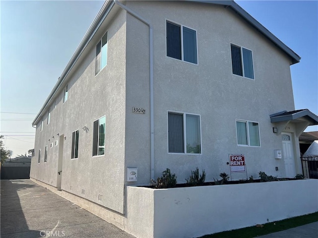 view of home's exterior with fence and stucco siding