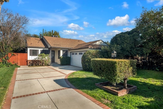 view of front of home with an attached garage, fence, a front lawn, and concrete driveway