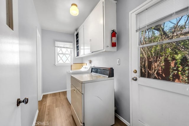 laundry room featuring cabinet space, washing machine and dryer, baseboards, and light wood-style flooring