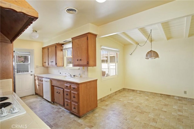 kitchen featuring white appliances, light countertops, hanging light fixtures, brown cabinets, and plenty of natural light