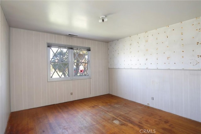 unfurnished room with wainscoting and wood finished floors