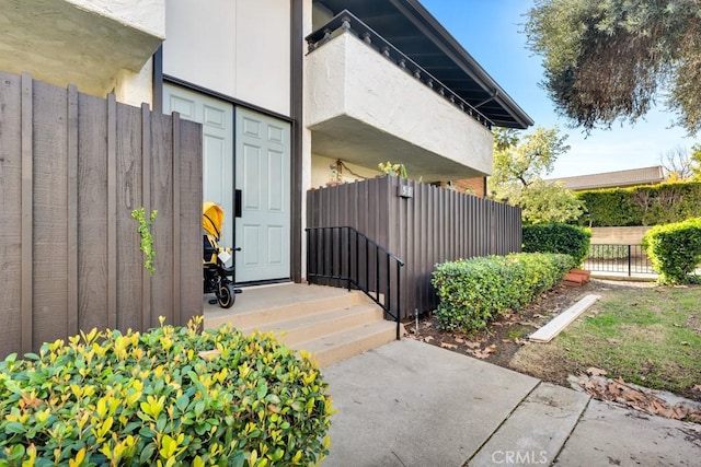 doorway to property featuring stucco siding and fence